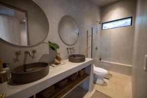 a bathroom with two sinks and a toilet and mirrors at Garden Treehouse Ikhaya in Refundores +20 photos