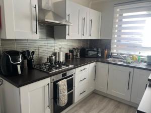 a kitchen with white cabinets and a stove top oven at 60 Springfield Road in Stornoway