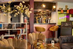 a room with a bar with chairs and a table at Hotel Arc-En-Ciel Colmar Contact Hotel in Colmar