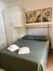 a bedroom with a green bed with two towels on it at Aconchego Corrêas in Petrópolis +7 photos