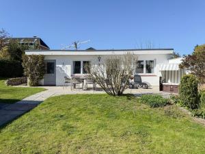 a white house with a table and chairs in the yard at Cozy Home in Timmendorfer Strand
