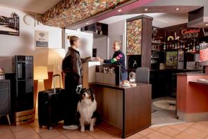 a man and a woman at a bar with a dog at Hotel Arc-En-Ciel Colmar Contact Hotel in Colmar