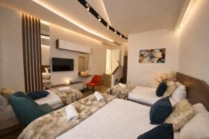 a hotel room with three beds and a television at Apel Luxury in Niš