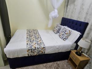 a bedroom with a bed with a blue headboard and pillows at Favoured Brink in Nairobi