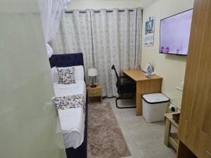 a bedroom with a bed and a desk and a television at Favoured Brink in Nairobi