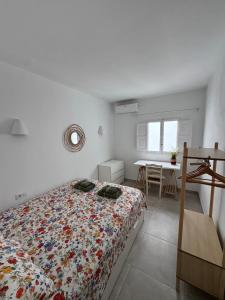 a white bedroom with a bed and a table at Céntrico duplex con piscina in Jávea +24 photos