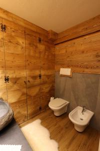 a bathroom with wooden walls and a toilet and a sink at Maison Rita e Cello in La Salle +8 photos