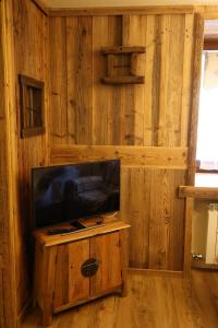 a living room with a tv and a wooden wall at Maison Rita e Cello in La Salle