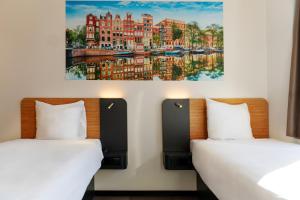 two beds in a room with paintings on the wall at easyHotel Amsterdam Zaandam in Zaandam