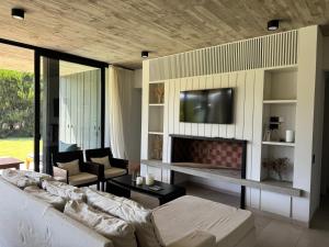a living room with a couch and a tv at Casa Cortaderas, Barrio Quequén Chico in Necochea