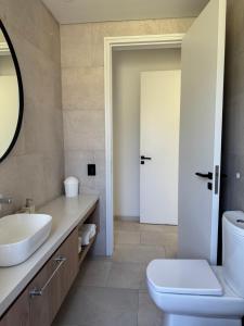 a bathroom with a toilet and a sink and a mirror at Casa Cortaderas, Barrio Quequén Chico in Necochea +15 photos