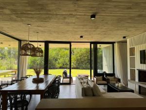 a dining room and living room with a table and chairs at Casa Cortaderas, Barrio Quequén Chico in Necochea
