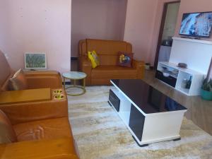 a living room with a couch and a tv at Cae Cozy Home in Karatu