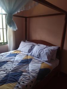 a bed with a quilt on it with a window at Cae Cozy Home in Karatu