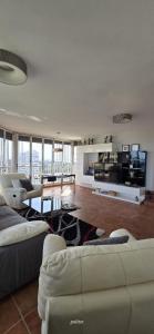 a living room with a couch and a tv at Three Horizons Penthouse El Saler in Valencia
