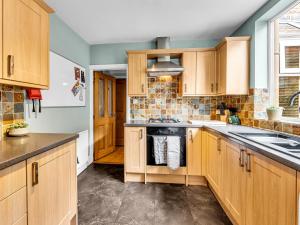 a kitchen with wooden cabinets and a sink at Spacious Stoke Townhouse 3BR Near Hospital & M6 with Parking in Stoke on Trent