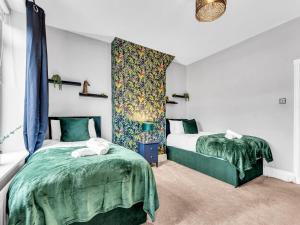 a bedroom with two beds with green comforters at Spacious Stoke Townhouse 3BR Near Hospital & M6 with Parking in Stoke on Trent