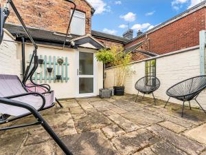 a patio with two chairs in front of a building at Spacious Stoke Townhouse 3BR Near Hospital & M6 with Parking in Stoke on Trent
