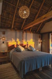 a bedroom with a large bed with a chandelier at Mangle Rojo Palafitos in La Manzanilla