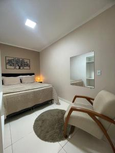 ein Schlafzimmer mit einem Bett, einem Stuhl und einem Spiegel in der Unterkunft Apto do Xavier in Juazeiro