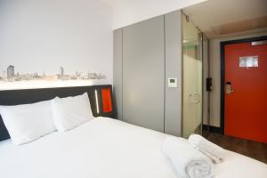 a bedroom with a white bed and a red door at easyHotel Sheffield in Sheffield