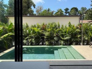 a swimming pool in front of a house with palm trees at Demaya Villa 5 in Ko Phangan
