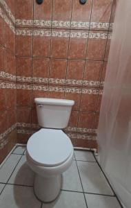a bathroom with a white toilet in a tile wall at Volcano Hostal in Rivas