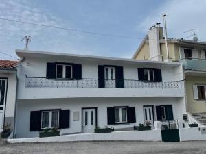 a white house with black shutters and a balcony at Raízes da Serra - Casa Lapa in Lapa dos Dinheiros