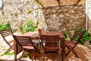 a wooden table with four chairs and a stone wall at La Calma de Vilo in Periana