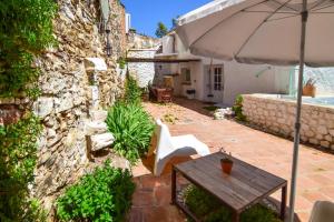 a patio with a wooden table and an umbrella at La Calma de Vilo in Periana