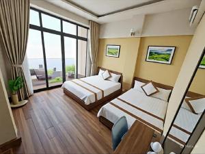 a hotel room with two beds and a large window at Brother Friendly - Gia Cat Long Hotel in Cat Ba