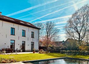 a house with a swimming pool in front of it at B&B De Rooman in Sint-Gillis-Waas