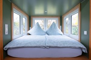 a bed in a room with three windows at Ilsehof Tiny-House Mimi in Osterwieck