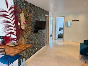 a living room with a wall with a tropical wallpaper at Le Nid du Cotentin - Maison moderne & calme in Les Pieux