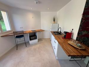 a kitchen with a wooden counter and a refrigerator at Le Nid du Cotentin - Maison moderne & calme in Les Pieux +3 photos