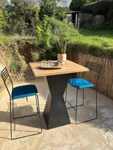 a wooden table with two blue chairs and a table at Le Nid du Cotentin - Maison moderne & calme in Les Pieux