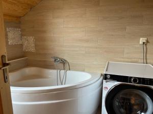 a washing machine next to a white tub in a bathroom at Ethno holistic village Apače - Nature Retreat in Slovenia in Apače