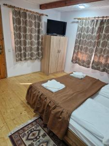 a room with a bed with a table and a tv at Casa Marinela in Haţeg