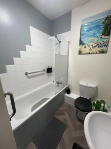 a bathroom with a tub and a toilet and a sink at Full Apartment in the Heart of Margate in Margate