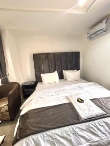 a bedroom with a large bed with a leather headboard at Saint Apartment by Bento in Gwarinpa