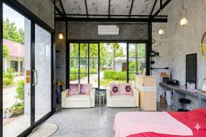 a bedroom with a bed and two chairs and windows at Ban Tew Kao in Ban Nong Chaeng