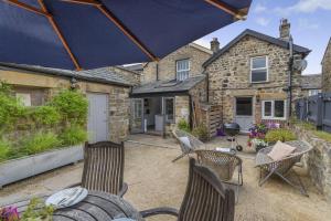 a patio with chairs and an umbrella in front of a house at 4 Bed in Masham oc-w32087 in Masham