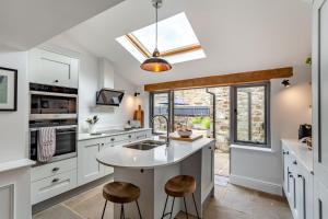 a kitchen with white cabinets and a sink and stools at 4 Bed in Masham oc-w32087 in Masham