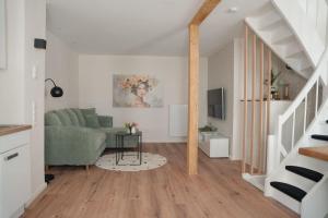 a living room with a green couch and a staircase at Altstadt Suite Bitburg in Bitburg