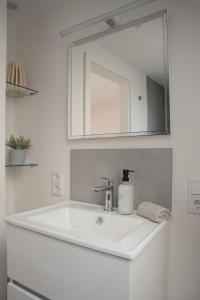 a bathroom with a white sink and a mirror at Altstadt Suite Bitburg in Bitburg +29 photos
