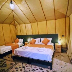 a bedroom with two beds in a tent at Sunrise Dunes Luxury Camp in Merzouga