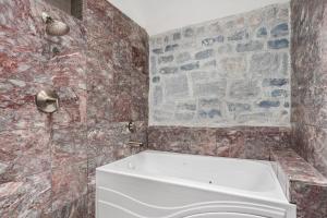 a bathroom with a white tub and a stone wall at Sonoma Stonehouse Hotel in Santa Rosa