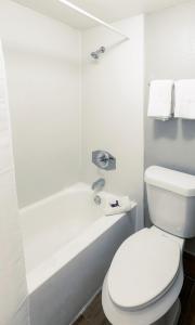 a white bathroom with a toilet and a bath tub at Home Suites Culebra in San Antonio