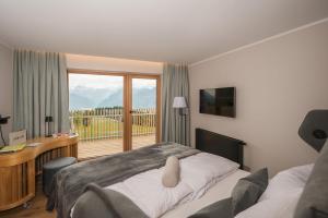 a bedroom with a bed and a desk and a window at Berghotel Predigstuhl in Bad Goisern