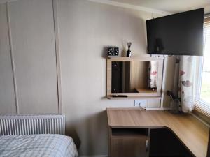 a bedroom with a desk with a tv on the wall at The Bay View in Eyemouth